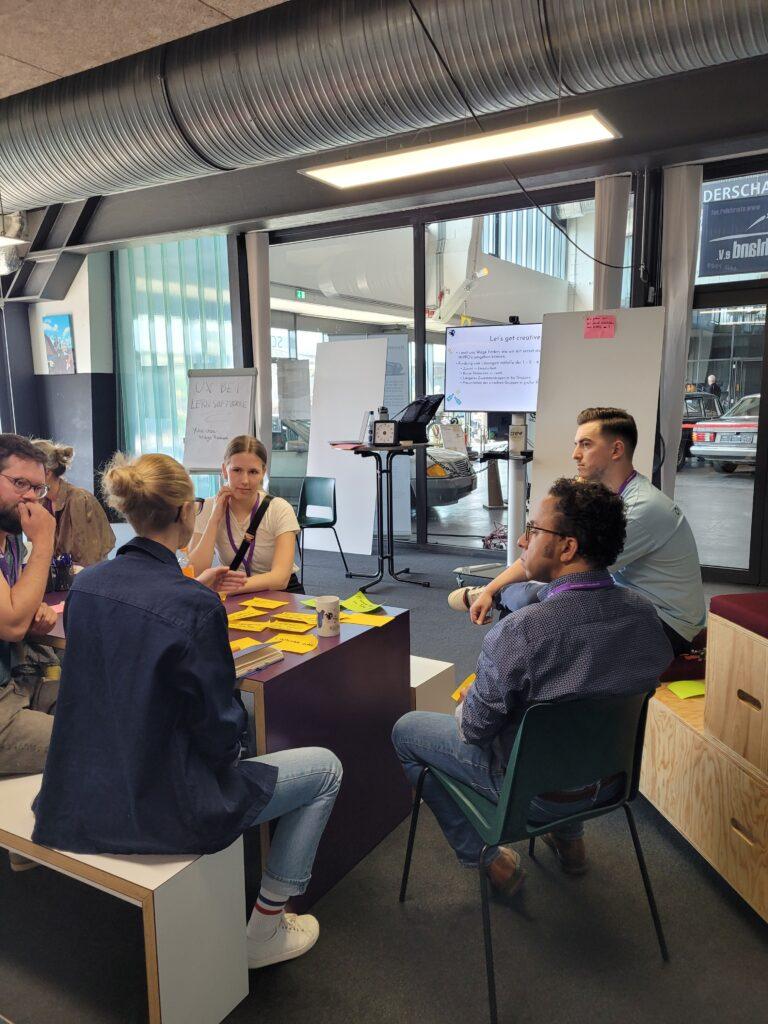Workshop-Teilnehmer:innen sitzen zusammen und diskutieren ihre Empfehlungen für UX-Designer